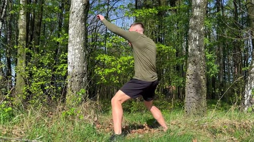 Athletic Man Trains Martial Arts Outdoors in the Forest Performing Boxing Moves