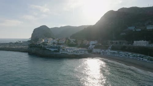 Aerial Sliding Shot of Sea Coast with Small Town and Marina Steep Cliffs in Background View Against