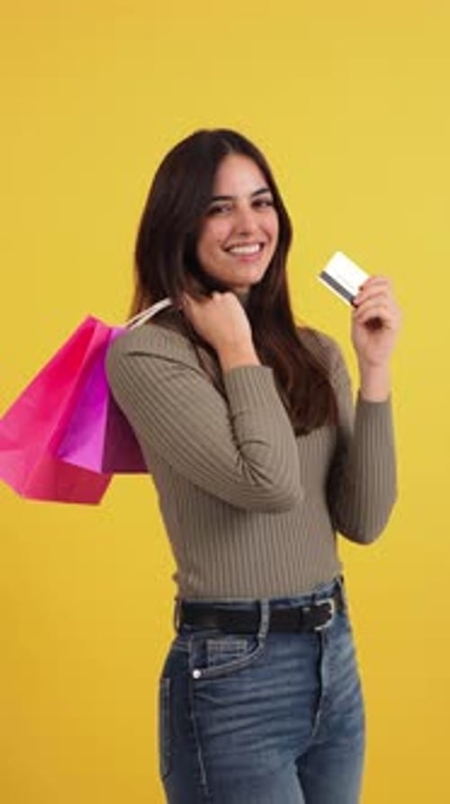 Excited Young Woman Happily Showing Off Credit Card and Colorful Shopping Bags in Cheerful