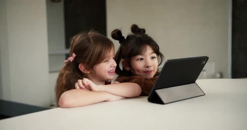 Two Diverse Sisters Using the Tablet Digital Computer for Elearning or Watching Cartoons