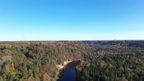 Aerial view of a winding river amidst autumn foliage