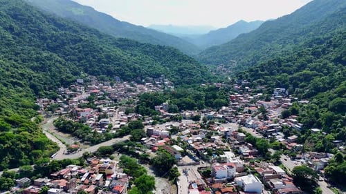 Aerial drone view of the cuale river flowing through a small town in puerto vallarta, mexico