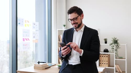 Businessman Smiling While Using Smartphone in Modern Office Environment