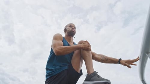 Man, fitness and stretching legs in city with earphones, exercise start or preparation for training