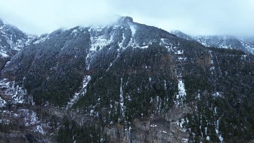 Snow-covered mountain range with forest and fog in Canfranc-Estación, Spain