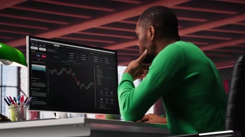 Man Analyzes Financial Data on Computer Screen