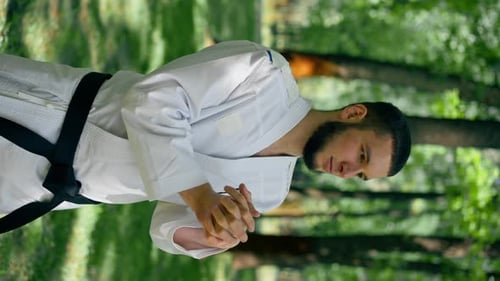 Vertikales Video draußen im Park bei sonnigem Wetter Der junge Karate-Junge wärmt sich auf und nutzt den