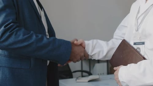 Male Hospital Executive and Female Doctor Shaking Hands after Meeting