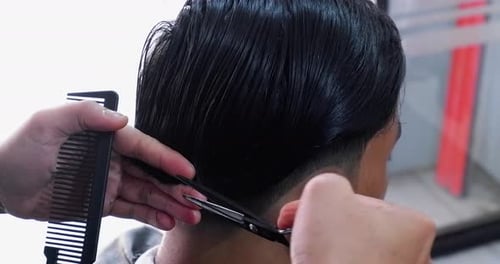 A hairdresser makes a mens haircut in a barbershop. Close up process.