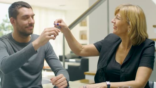 Realtor Handing Keys to Young Man Indoors