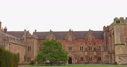 View of old medieval architecture of Bishop's Palace with Chapel and green Croquet Lawn in Wells, En