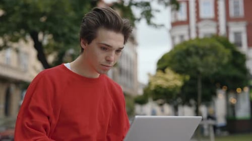 Excited Young Adult Using Laptop in City