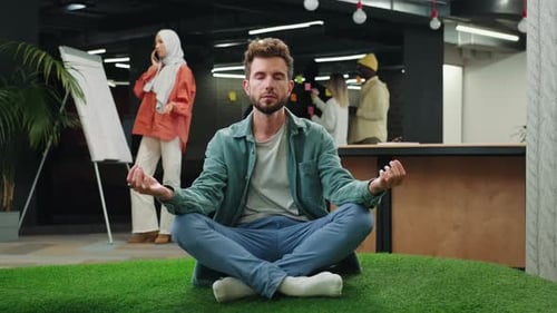 European Businessman Meditates in the Office Sitting on the Floor