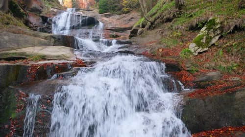 Water flowing over rocks in autumn forest waterfall