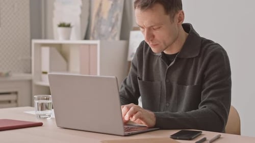 Pensive Businessman Working on Laptop in Office