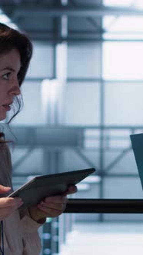 Vertical Video Team of Technicians Working in Server Farm Using Laptops to Analyze Data