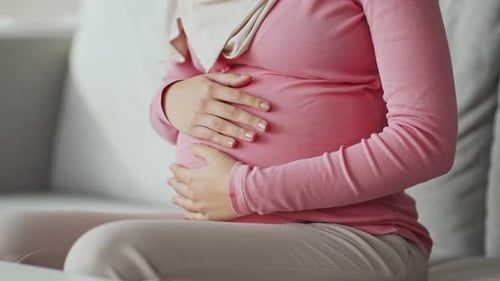 Pregnant Woman Comfortably Sitting and Holding Her Belly