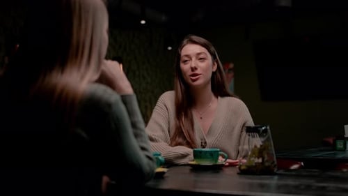 two young girlfriends sit relaxed in a hookah bar and cheerfully discuss something the concept