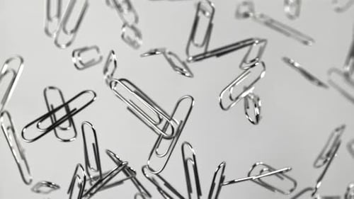 Silver Paper Clips Floating Against White Background in Studio
