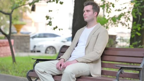 Man Sitting on Park Bench in Urban Setting