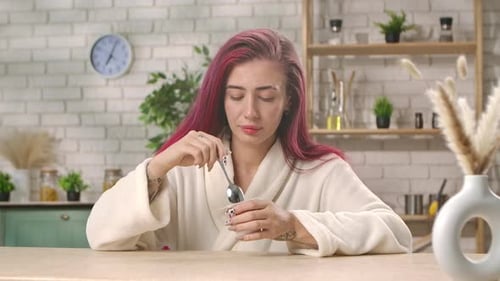 Woman in Robe Eats Yogurt in Kitchen