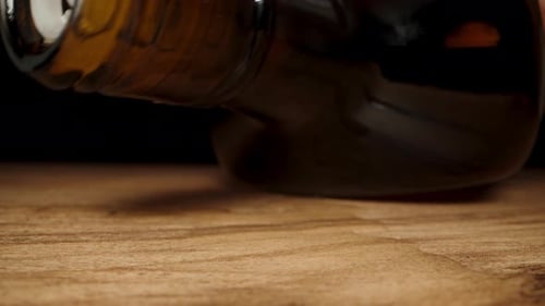 I place the empty black whiskey bottle on the table, and the last drops are dripping from it onto