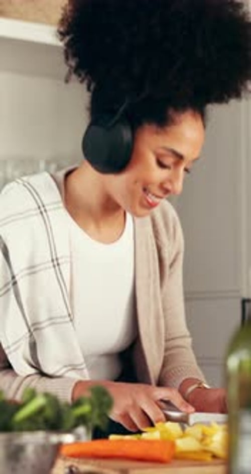 Woman Prepares Vegetables in Kitchen With Headphones On
