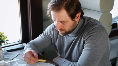 Handsome Bearded Man Has Lunch Sitting at the Kitchen Table at Home Male Eating French Fries