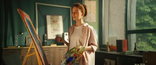 Young Woman Painting on Canvas in Sunny Studio