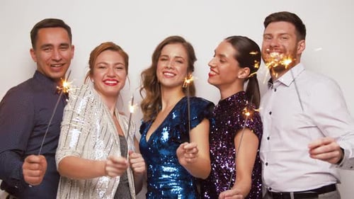 Group of friends celebrating with sparklers and dancing
