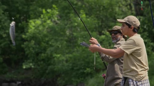 Glücklicher asiatischer Großvater und Enkel fangen auf Sommerreise Wildfische