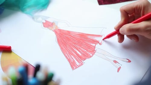 Fashion Designer Sketching a Red Dress on Paper