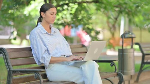 Young Woman Working on Laptop in Park
