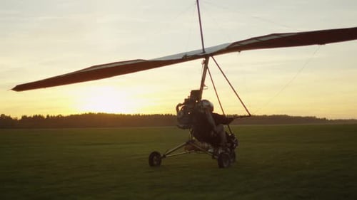 Hang Gliding at Sunset Over Green Field