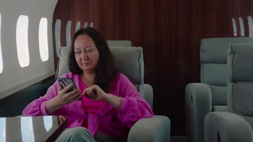 Woman on Private Jet Using Smartphone