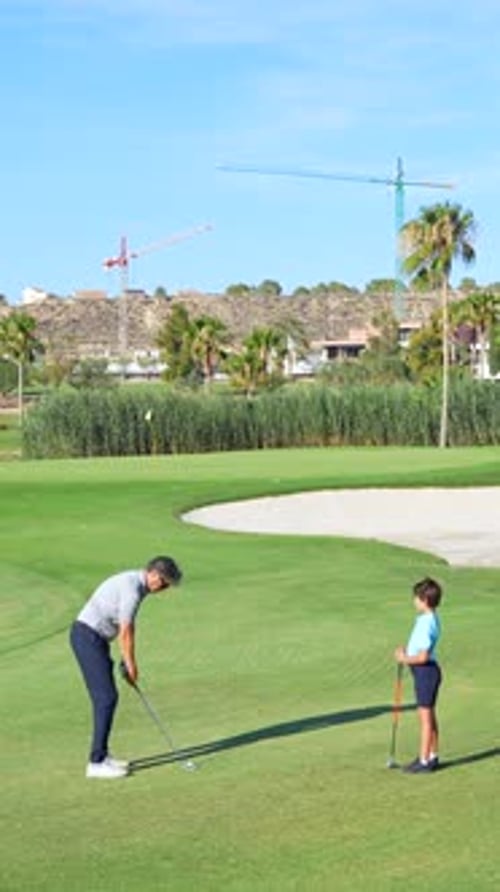 Father and Child Playing Golf on Sunny Green Course