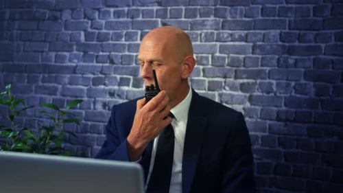 Security manager talking on a walkie talkie two way radio calling security guards from a control roo
