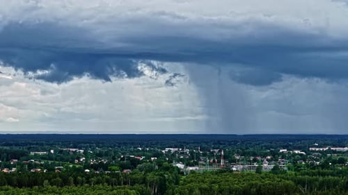 Storm clouds pouring rain on cityscape, aerial time lapse view