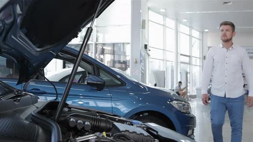 Un homme regarde le compartiment moteur de la voiture chez le concessionnaire