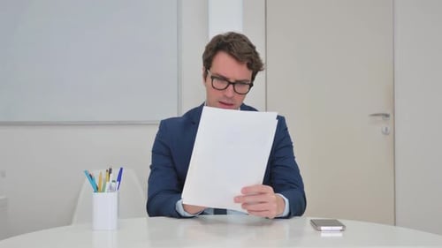 Man Reviews Documents and Smiles at Desk