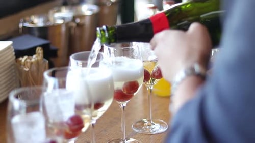 Person pours champagne into glasses at a restaurant.
