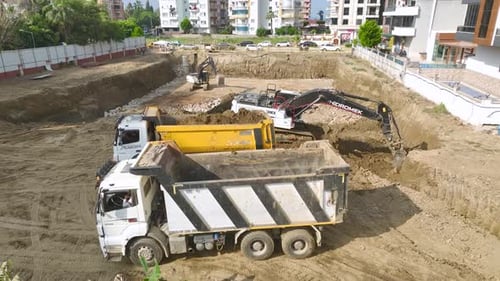 Excavator Loading Dump Trucks at Construction Site