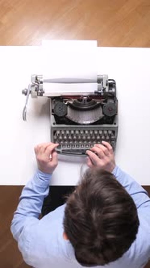 Vertical Video Man Typing on a Classic Manual Typewriter at a Desk Busy Writing on Paper Creating