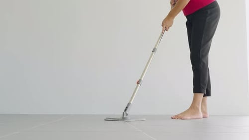 Woman Mops the Indoor Floor Cleaning the Front Area of Her Home with a Mop and Rag Housewife