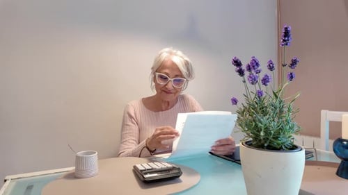Senior Woman Calculating Domestic Expenses with Calculator