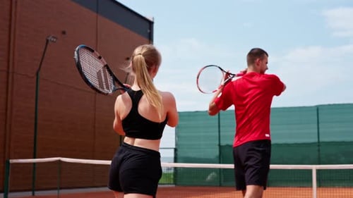 Young Adults Playing Tennis on Outdoor Court