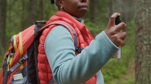 Woman sprays bug repellent in forest
