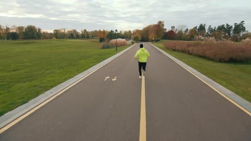 Back View of Male Athlete Running on Dividing Line on Bicycle Path in Park