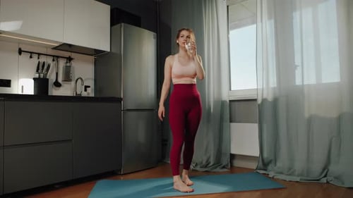 Woman Drinks Water on Yoga Mat Indoors