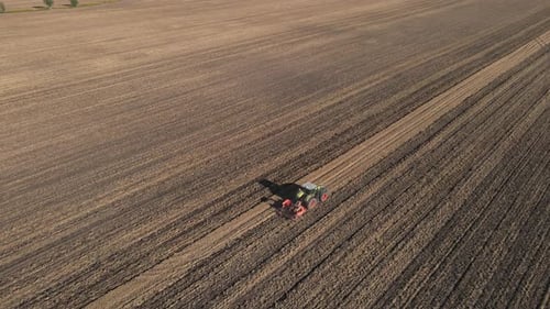 Tractor working on agricultural field, plowed farmland